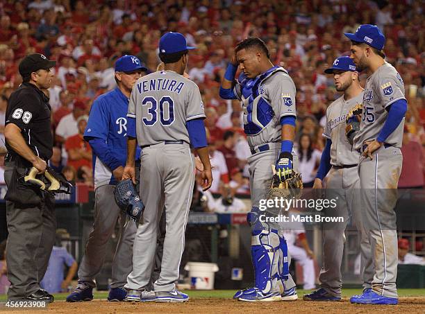 Salvador Perez of the Kansas City Royals rubs his head after being hit with the bat of Josh Hamilton of the Los Angeles Angels of Anaheim during Game...