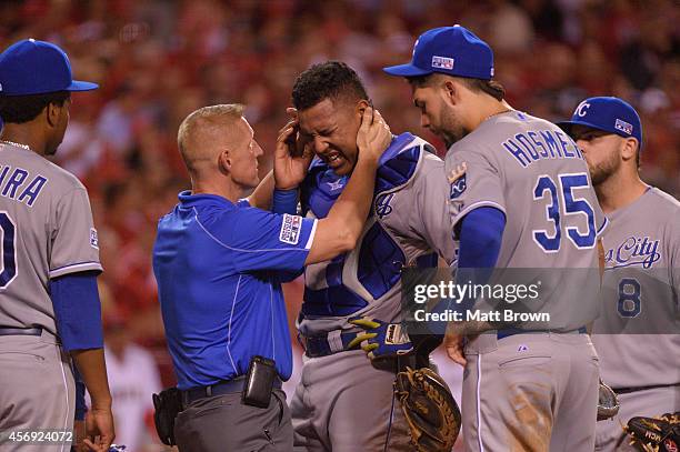 Salvador Perez of the Kansas City Royals is checked by a trainer after being hit in the head with the bat of Josh Hamilton of the Los Angeles Angels...