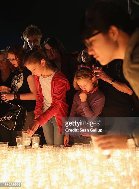 People arrive to light candles on Augustplatz square during commemorations marking the 25th anniversary of the mass protests in Leipzig that preceded...