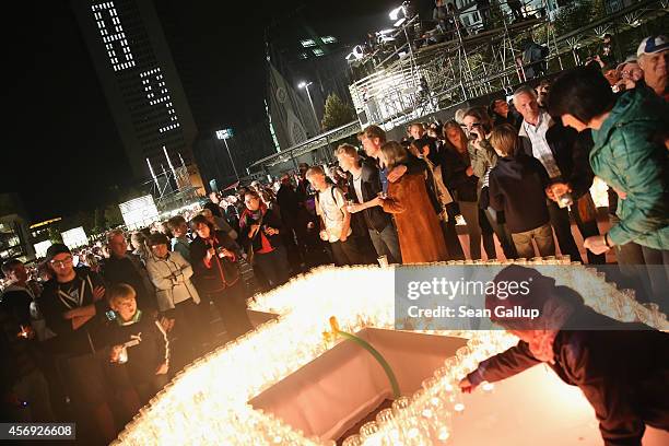 People arrive to light candles on Augustplatz square during commemorations marking the 25th anniversary of the mass protests in Leipzig that preceded...