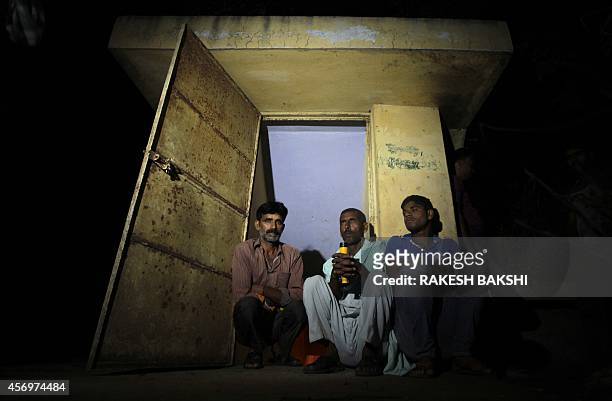 Indian border villagers sit at the entrance of an Indian army bunker as they take shelter during cross-border firing at Abdullian village of RS Pura...