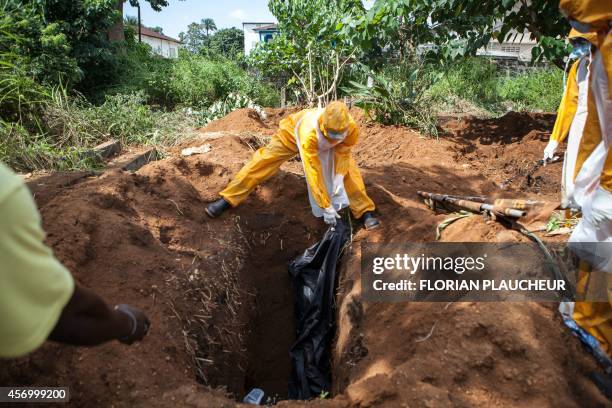 Team of funeral agents specialised in the burial of victims of the Ebola virus put a body in a grave at the Fing Tom cemetery in Freetown, on October...