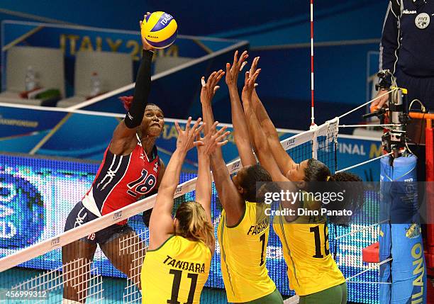 Bethania De La Cruz De Pena of Dominican Republic spikes the ball against Tandara Caixeta Fabiana Claudino and Fernanda Rodrigues of Brazil during...