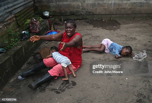 Sophia Doe sits with her grandchildren Beauty Mandi, 9 months and Arthuneh Qunoh , while watching the arrival an Ebola burial team to take away the...