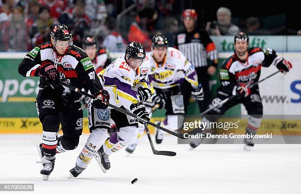 Philip Gogulla of Koelner Haie and Kyle Sonnenburg of Krefeld Pinguine battle for the puck during the DEL Ice Hockey match between Koelner Haie and...
