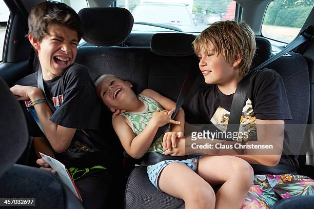 3 boys playing in the back seat of a car - back of car stock-fotos und bilder