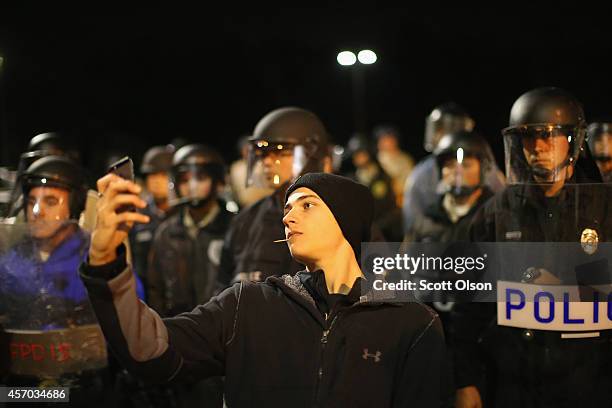 Demonstrator takes a selfie in front of a police line during a protest outside the Ferguson police department on October 10, 2014 in Ferguson,...