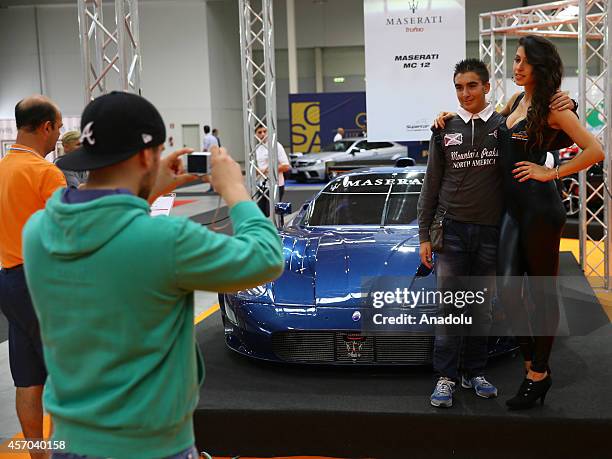 Man poses with a model in front of a Maserati MC-12 presented during the Supercar Roma Auto Show in Rome, capital city of Italy, on October 10, 2014.