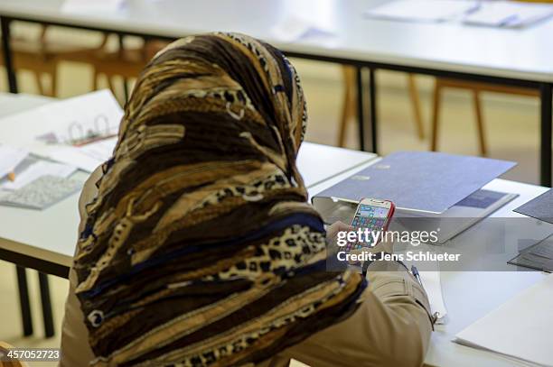 Unidentified Syrian refugee uses a mobile phone during a break in a German language class at the refugee center on December 10, 2013 in Friedland,...