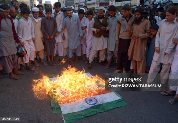 Pakistani supporters of banned Islamic group Jamaat-ud-Dawa watch as Indian flags burn during a protest against the execution of Bangladeshi Islamist...