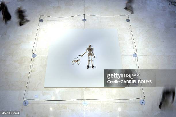 People walk around a piece of art by Gino de Dominicis called "Time, Error, Space" representing the skeleton of a man walking with his dog as part of...
