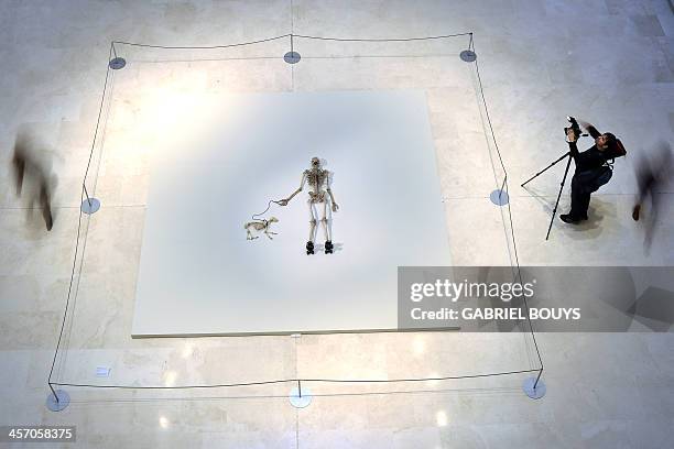 People walk around a piece of art by Gino de Dominicis called "Time, Error, Space" representing the skeleton of a man on rollerblades and his dog as...