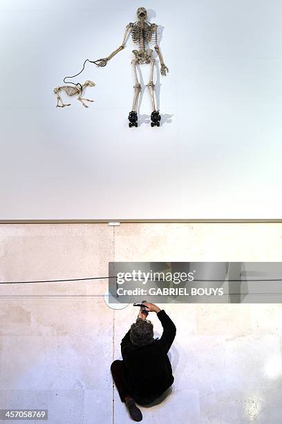 Person takes a picture of a piece of art by Gino de Dominicis called "Time, Error, Space" representing the skeleton of a man on rollerblades and his...