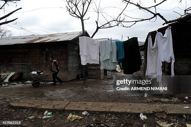 Roma woman pushes a cart at a Roma camp which is being dismantled in the Serb-majority town of Leposavic in northern Kosovo on December 16, 2013....