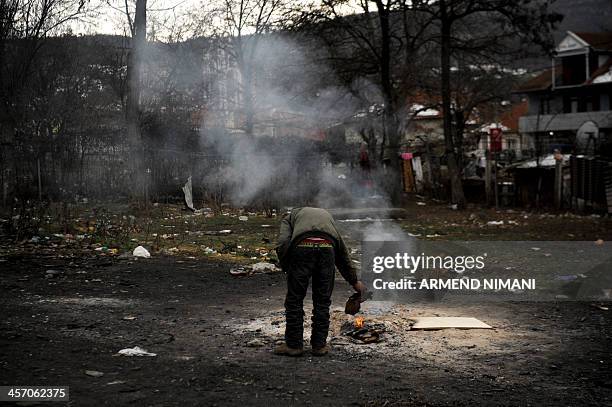 Roma man warms himself by a fire at a Roma camp in the Serb-majority town of Leposavic, northern Kosovo on December 16, 2013. Around 35 Roma, Ashkali...