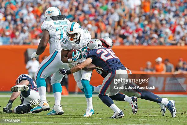 Daniel Thomas of the Miami Dolphins is tackled by Steve Gregory of the New England Patriots on December 15, 2013 at Sun Life Stadium in Miami...