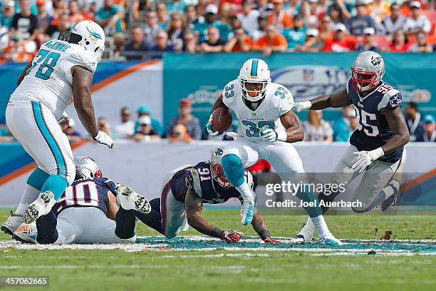 Daniel Thomas of the Miami Dolphins runs with the ball past the attempted tackle of Jamie Collins of the New England Patriots on December 15, 2013 at...