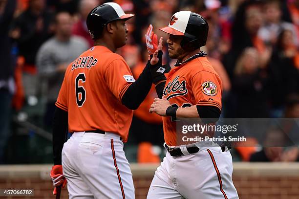 Steve Pearce celebrates with teammate Jonathan Schoop after scoring on a sacrifice fly to center field hit by Caleb Joseph of the Baltimore Orioles...