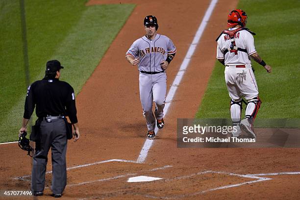 Buster Posey of the San Francisco Giants runs home to score on a sacrafice fly in the third inning against the St. Louis Cardinals during Game One of...