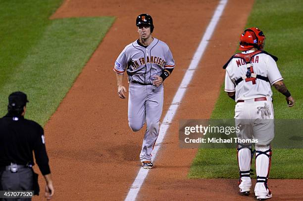 Buster Posey of the San Francisco Giants runs home to score on a sacrafice fly in the third inning against the St. Louis Cardinals during Game One of...