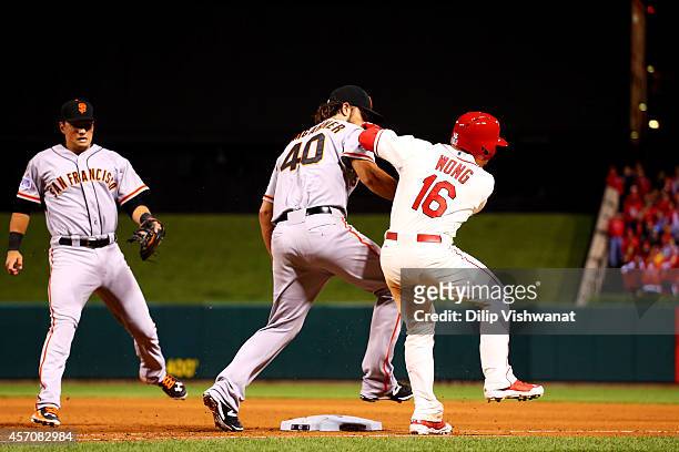 Madison Bumgarner of the San Francisco Giants tags Kolten Wong of the St. Louis Cardinals out in the seventh inning during Game One of the National...