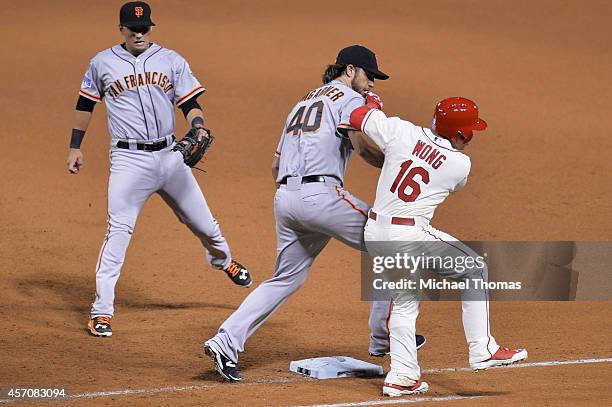 Madison Bumgarner of the San Francisco Giants tags Kolten Wong of the St. Louis Cardinals out in the seventh inning during Game One of the National...