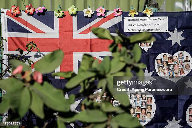 An Australian flag with the photos victims of the Bali bombing is seen across the street from the Bali Bombing Memorial Monument on October 12, 2014...