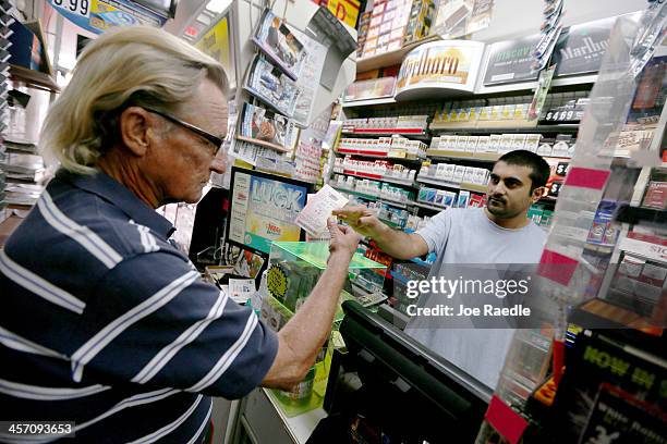 Richard Mcenery purchases Mega Million lottery tickets from Hiral Patel at Circle News Stand on December 16, 2013 in Hollywood, Florida. The Mega...