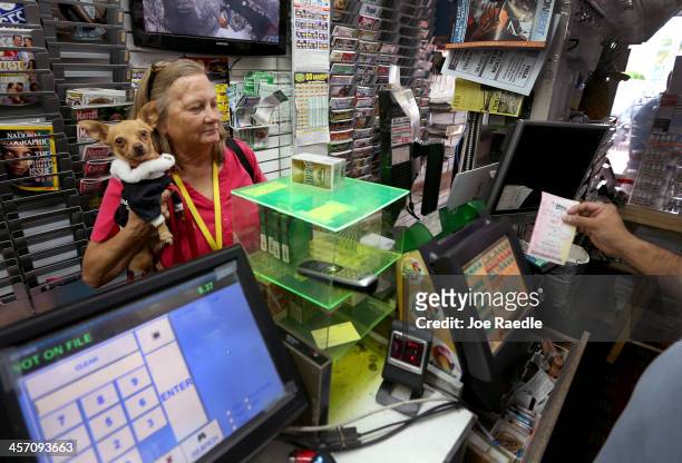 Marie Steele holds her dog, "Little Bit", as she purchases a Mega Million lottery ticket at Circle News Stand on December 16, 2013 in Hollywood,...
