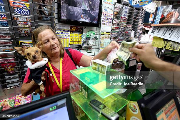 Marie Steele holds her dog, "Little Bit", as she purchases a Mega Million lottery ticket at Circle News Stand on December 16, 2013 in Hollywood,...