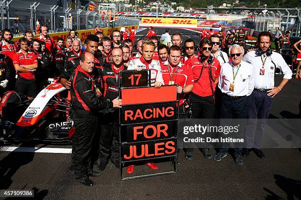 Max Chilton of Great Britain and Marussia stands with his team next to a tribute to Jules Bianchi of France and Marussia following his accident at...