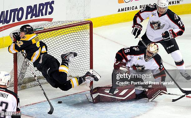 David Pastrnak, left, of the Providence Bruins, goes flying into the cross bar of Providence's goal as Portland goaltender Mike McKenna and...