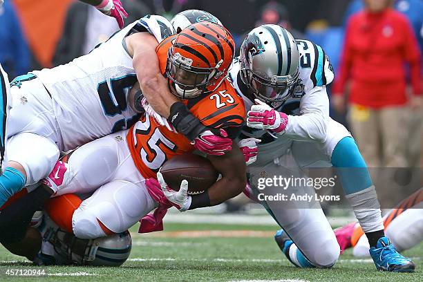 Giovani Bernard of the Cincinnati Bengals is tackled by Luke Kuechly of the Carolina Panthers and Melvin White of the Carolina Panthers during the...