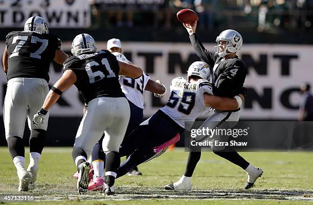 Derek Carr of the Oakland Raiders throws the ball as he is hit by Andrew Gachkar of the San Diego Chargers at O.co Coliseum on October 12, 2014 in...