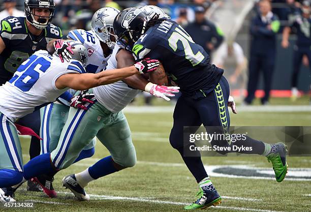 Running back Marshawn Lynch of the Seattle Seahawks is tackled by defensive back Sterling Moore, free safety Barry Church and defensive end Jeremy...