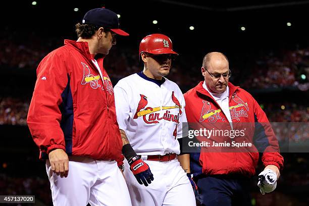 Yadier Molina receives attention from manager Mike Matheny and trainer Greg Hauck in the sixth inning during Game Two of the National League...