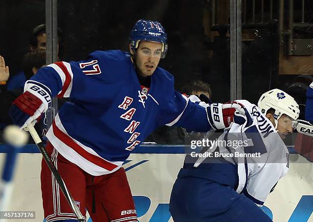 John Moore of the New York Rangers holds on to Brandon Kozun of the Toronto Maple Leafs at Madison Square Garden on October 12, 2014 in New York...