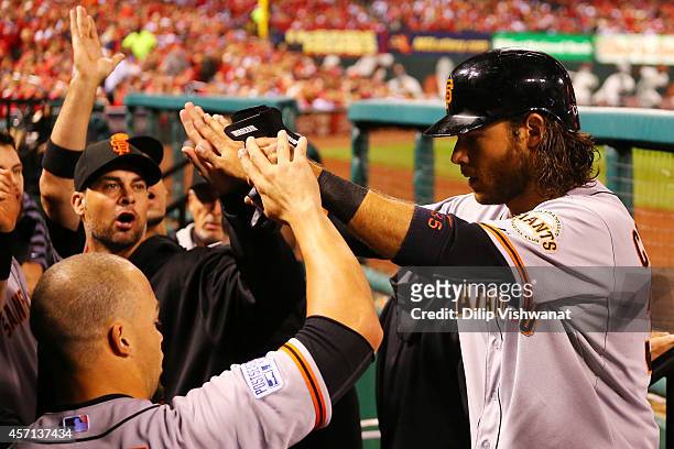 Brandon Crawford of the San Francisco Giants is welcomed to the dugout after scoring on a single by Gregor Blanco in the seventh inning against the...
