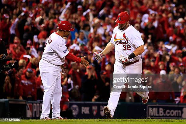 Matt Adams of the St. Louis Cardinals celebrates with third base coach Jose Oquendo after hitting a solo home run in the eighth inning against the...