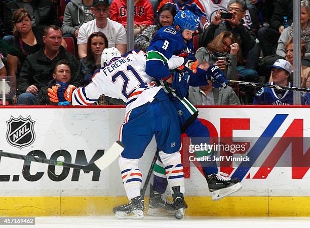 Andrew Ference of the Edmonton Oilers checks Zack Kassian of the Vancouver Canucks into the boards during their NHL game at Rogers Arena October 11,...