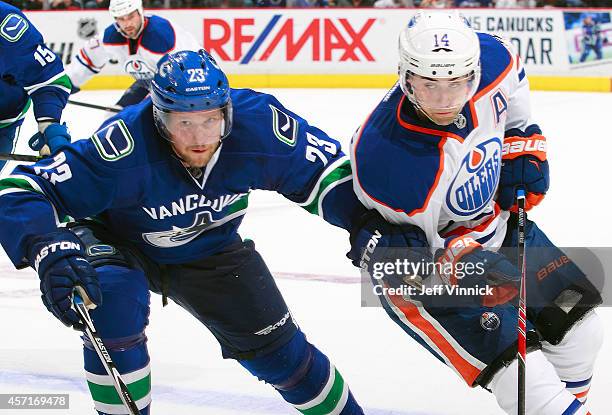 Alexander Edler of the Vancouver Canucks and Jordan Eberle of the Edmonton Oilers skate up ice during their NHL game at Rogers Arena October 11, 2014...