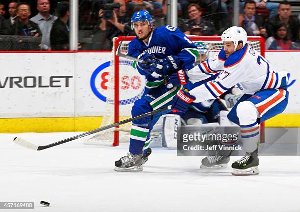 Boyd Gordon of the Edmonton Oilers checks Christopher Tanev of the Vancouver Canucks as he passes the puck up ice during their NHL game at Rogers...
