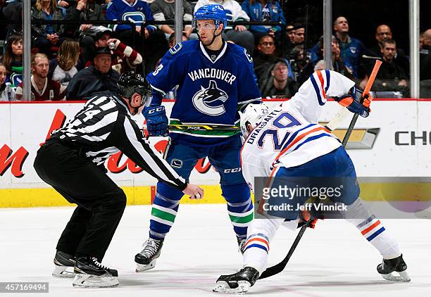 Linesman Lonnie Cameron prepares to drop the puck between Nick Bonino of the Vancouver Canucks and Leon Draisaitl of the Edmonton Oilers during their...