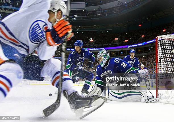 Kevin Bieksa and Ryan Miller of the Vancouver Canucks watch the rebound off the shot of Taylor Hall of the Edmonton Oilers during their NHL game at...