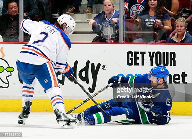 Jeff Petry of the Edmonton Oilers checks Daniel Sedin of the Vancouver Canucks to the ice during their NHL game at Rogers Arena October 11, 2014 in...