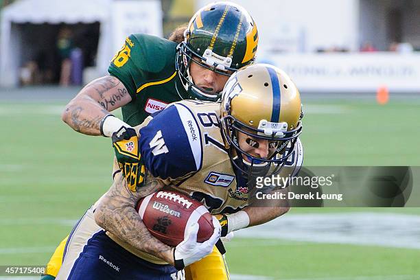 Aaron Grymes of the Edmonton Eskimos tries to tackle Rory Kohlert of the Winnipeg Blue Bombers during a CFL game at Commonwealth Stadium on October...