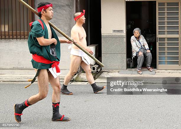 Japanese Shrine Parishioners of Matsubara team wears Fundoshi or loincloths as they walk past an elderly woman during the first day of the Nada...