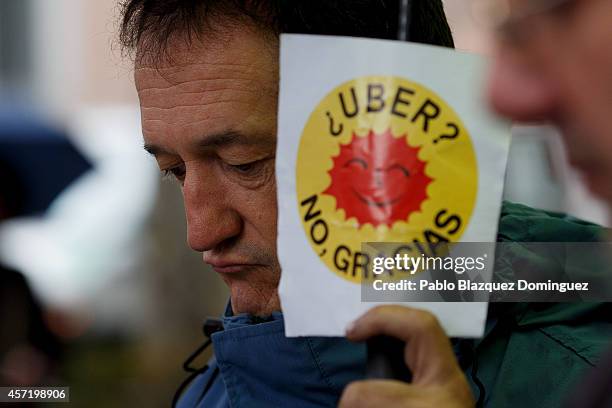 Taxi driver holds a placard reading 'UBER? No, thanks.' during a protest against new private cab 'UBER' application on October 14, 2014 in Madrid,...