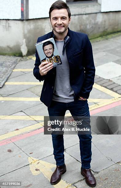 Shane Filan poses for pictures with his book 'My Side of Life: the Autobiography by Shane' as he leaves the ITV Studios on October 14, 2014 in...