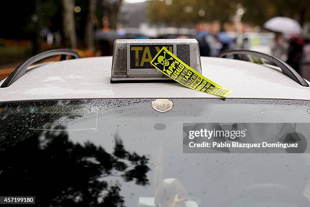 Sticker reading 'Applications Illegal. Taxi on war.' stands on the roof of a Taxi during a protest against new private cab 'UBER' application on...